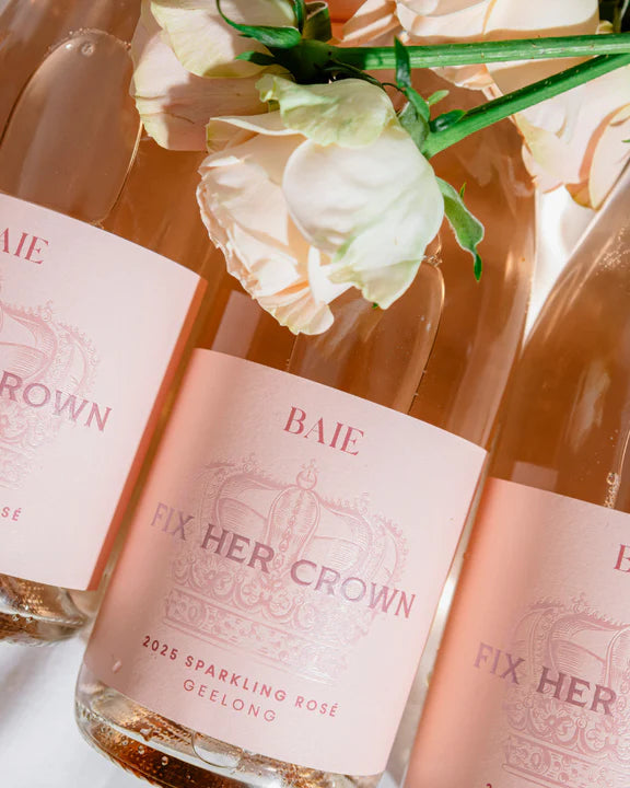 Three bottles of 'Fix Her Crown' sparkling rose wine with floral decorations on a light background.